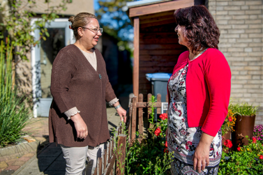 Twee personen praten met elkaar in de tuin.